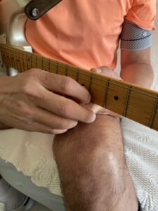 Arnaud qui essaie de se réapproprier sa guitare malgré son incapacité au membre supérieur gauche