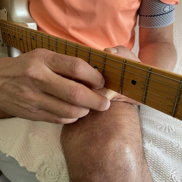 Arnaud qui essaie de se réapproprier sa guitare malgré son incapacité au membre supérieur gauche